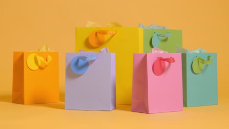 studio shot of colourful birthday party gift bags against yellow background 2