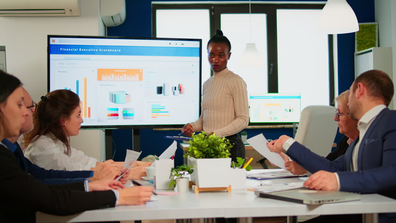 Black woman worker explaning company statistics in front of colleagues