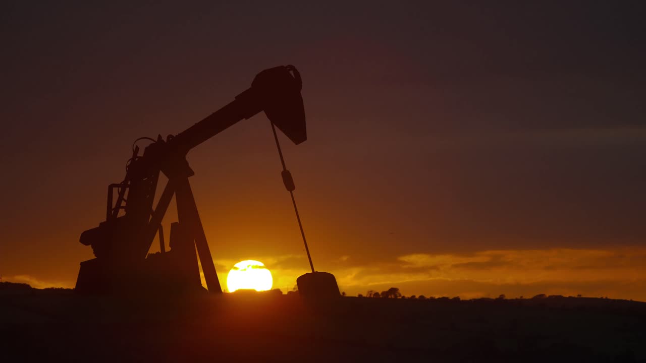 animación de la bomba de aceite trabajando durante la puesta del sol y el paisaje en el fondo