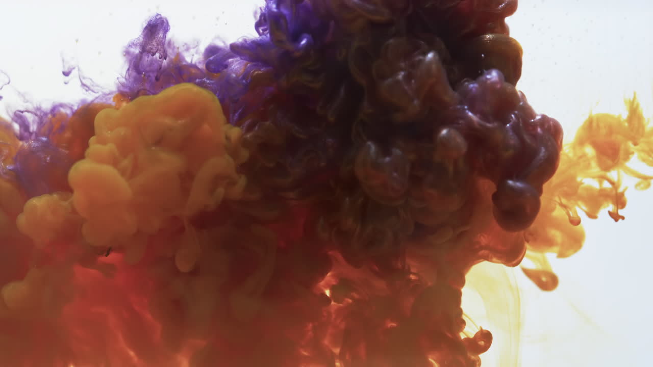 video en cámara lenta de tinta de acuarela púrpura y naranja mezclada con agua contra un fondo gris