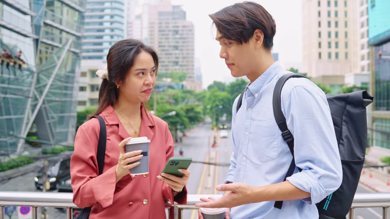 A man and woman in the city with coffee and a cellphone