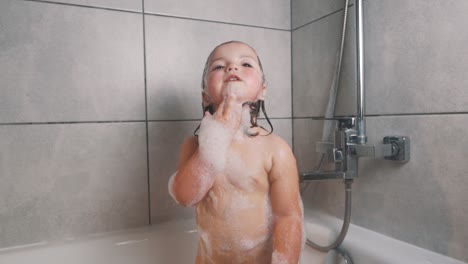 Niña-Bonita-En-Espuma-De-Baño-Cantando-Con-Un-Cepillo-De-Dientes-En-Las-Manos