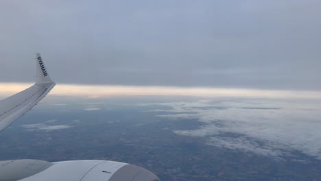 view of an airplane wing over fluffy clouds during a scenic flight at sunrise