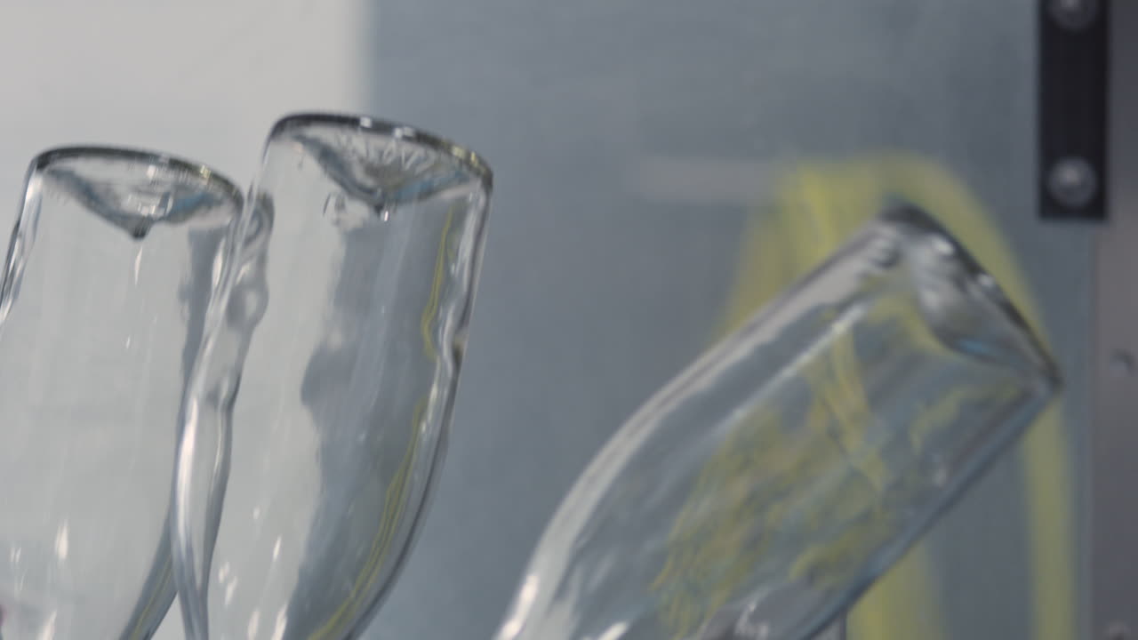Close-up of glass bottles lined up one by one, moving down an industrial production line, ready for the filling process.