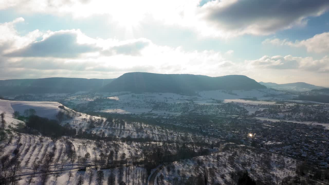 impresionantes vuelos aéreos a través de bosques y árboles que revelan un asombroso paisaje invernal con montañas cubiertas de nieve y sol en suabia, alemania