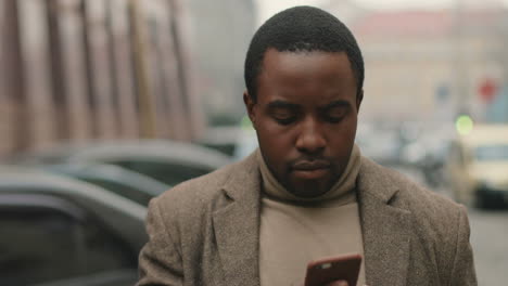 Close-up-view-of-African-American-businessman-wearing-coat-talking-on-the-phone-seriously-in-the-street-in-autumn