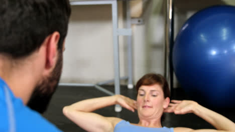 fisioterapeuta masculino ayudando a una paciente femenina durante el ejercicio