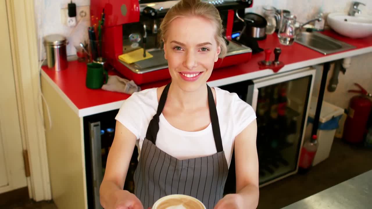 retrato de una camarera sonriente ofreciendo una taza de café en el mostrador