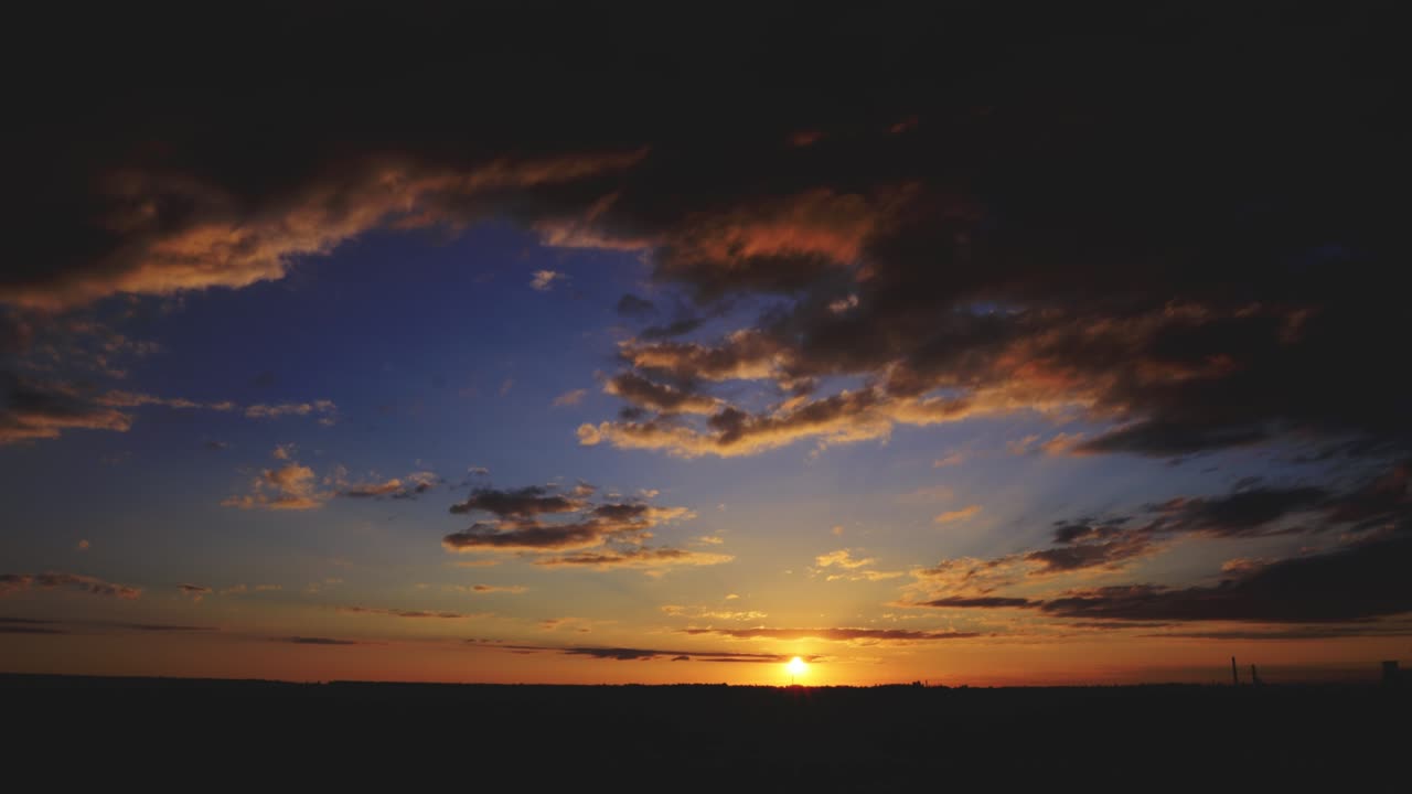 dramatic sunset against the background of clouds and fields and an industrial area, timelapse, shot with a wide-angle lens