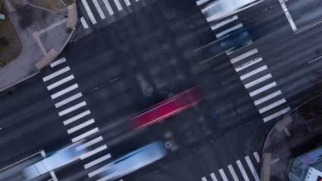 traffic speeds through busy intersection in riga, capital city of latvia, pedestrians come and go on corner; bird's eye top down view.