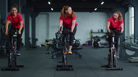 Grupo-De-Chicas-Atléticas-Realizando-Ejercicios-De-Entrenamiento-Aeróbico-En-Bicicleta-Estática-En-El-Gimnasio