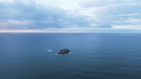 morning light reveals an isolated rocky island in the middle of the deep blue ocean