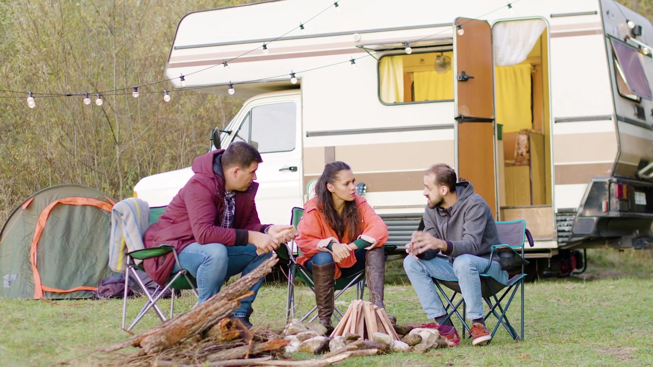 Mann forteller en historie til venner i campingstoler