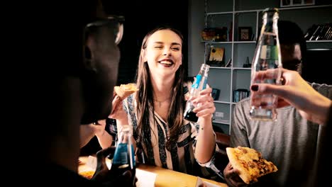 panning shot of young happy multiethnic friends making a toast, eating pizza and smiling at fun casual house party