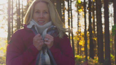 mujer madura envolviéndose en un abrigo cálido en una caminata por el campo de otoño o invierno - filmada en cámara lenta