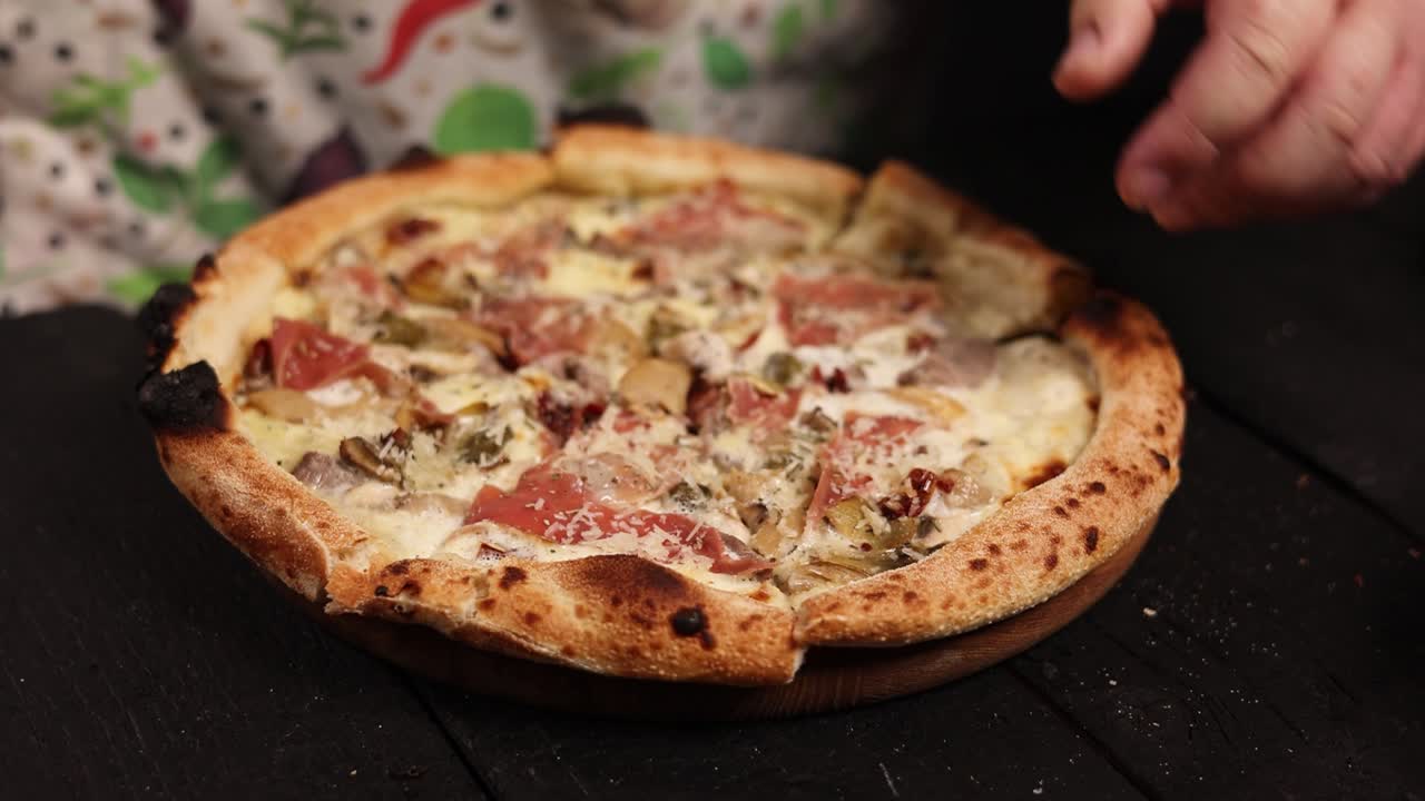 Chef che prepara una deliziosa pizza con prosciutto, funghi e pomodori secchi