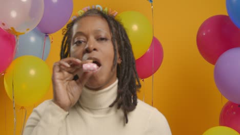 retrato de estudio de una mujer con una cinta para la cabeza de cumpleaños celebrando con globos y soplador de fiesta 1