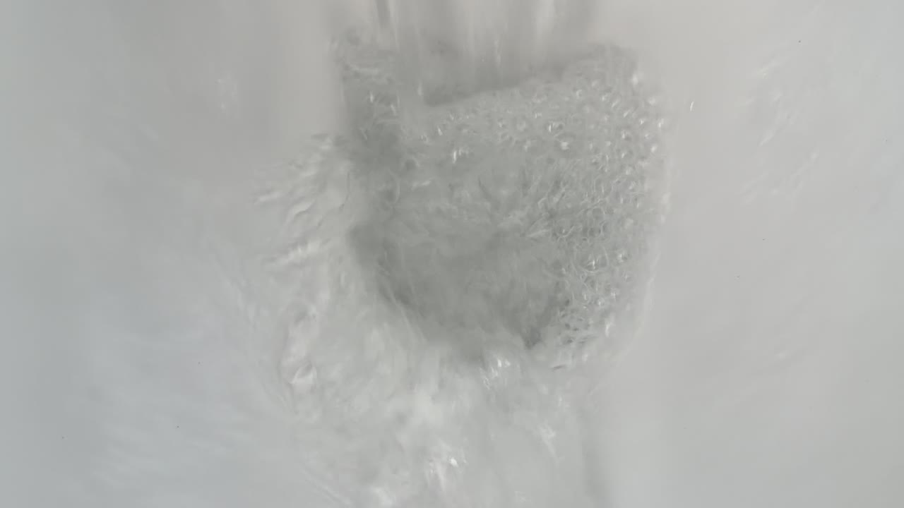 Primo piano dall'alto dell'acqua che vortica e defluisce all'interno di un water in ceramica bianca pulita