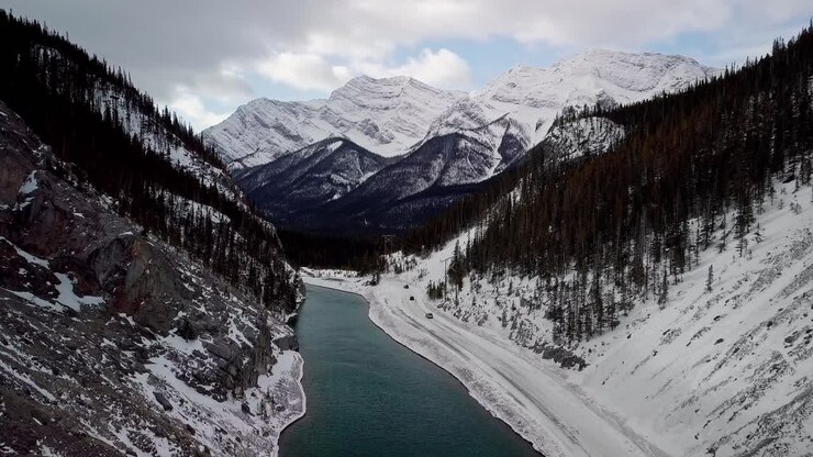 Persone che guidano sulla strada ghiacciata lungo il fiume Bow nel bacino idrico di Spray Lakes in Canada - vista aerea