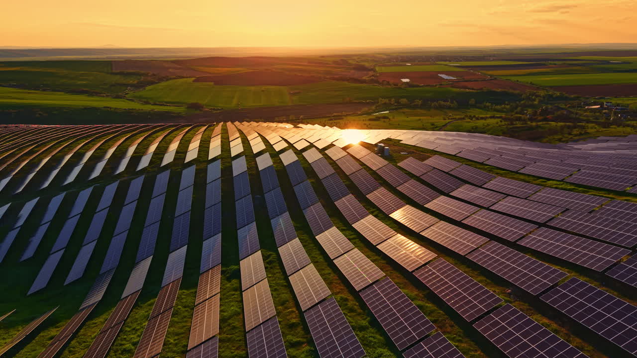 Solpaneler står på marker under solnedgang, hvilket fremhæver brugen af vedvarende energi i landbruget nær et landområde.