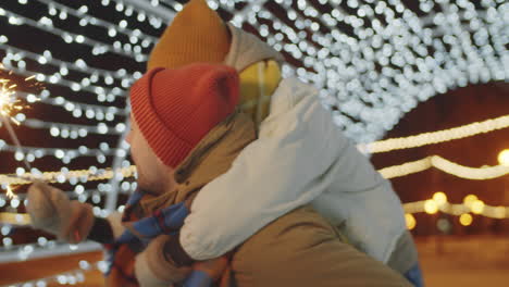 man giving piggyback ride and kissing girlfriend on christmas