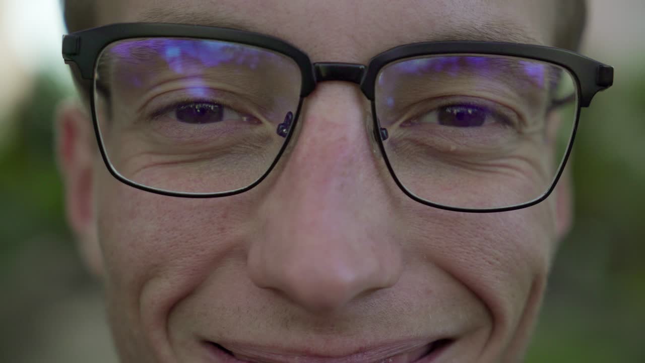 rostro masculino serio con gafas mirando a la cámara, sonriendo