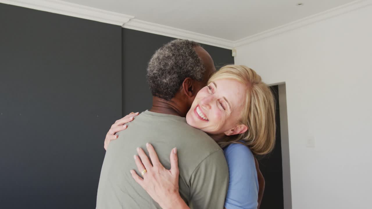 pareja de alto nivel de raza mixta abrazándose en casa