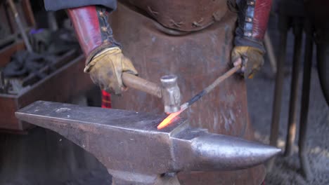 A-blacksmith-hammering-on-an-anvil-in-his-forge,-workshop,-close-up