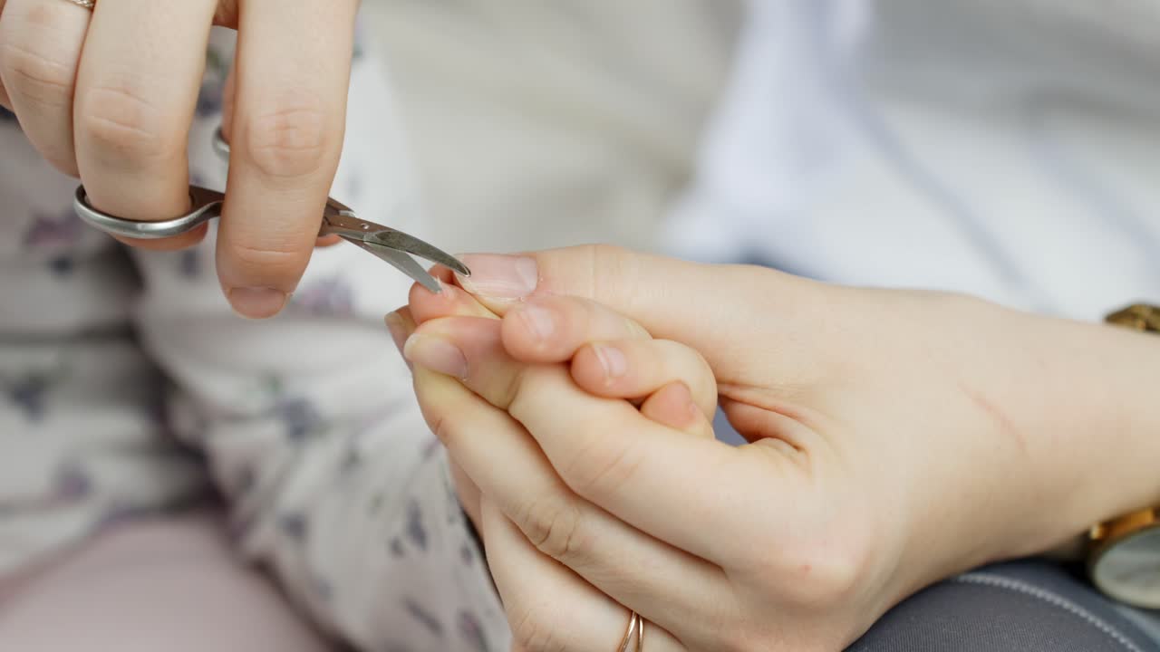 Adult carefully cutting toddler's fingernails, close-up, gentle moment indoors