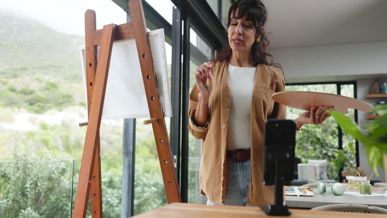Mulher artista gravando tutorial de pintura online no estúdio em casa