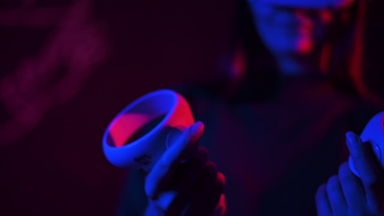 Una giovane donna che tiene in mano dei controller mentre indossa un visore VR, illuminazione rossa e blu. Rallentatore