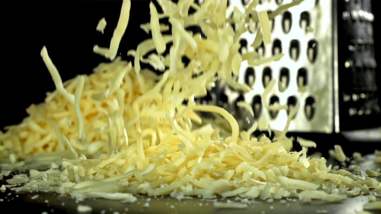 Fresh Grated Cheese Falling in Slow Motion with a Grater