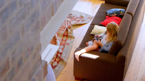 chica jugando juegos en el teléfono móvil en la sala de estar 4k