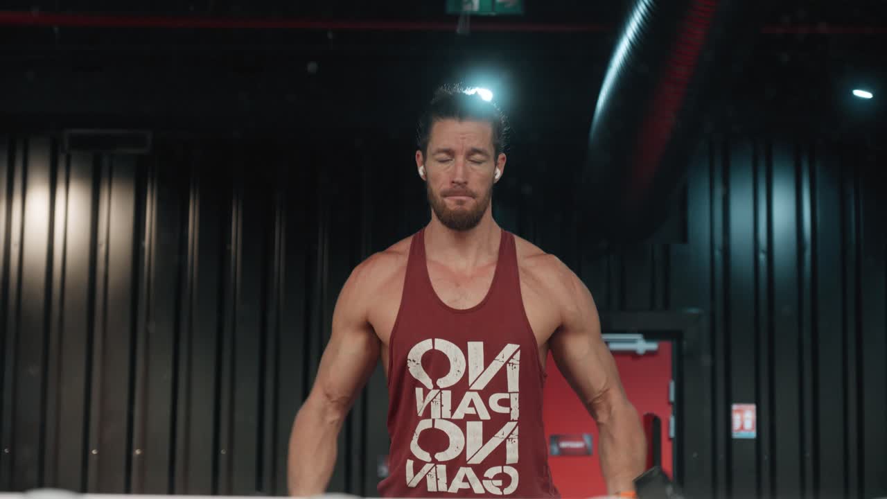 culturista musculoso haciendo elevaciones laterales con mancuernas delante de un espejo