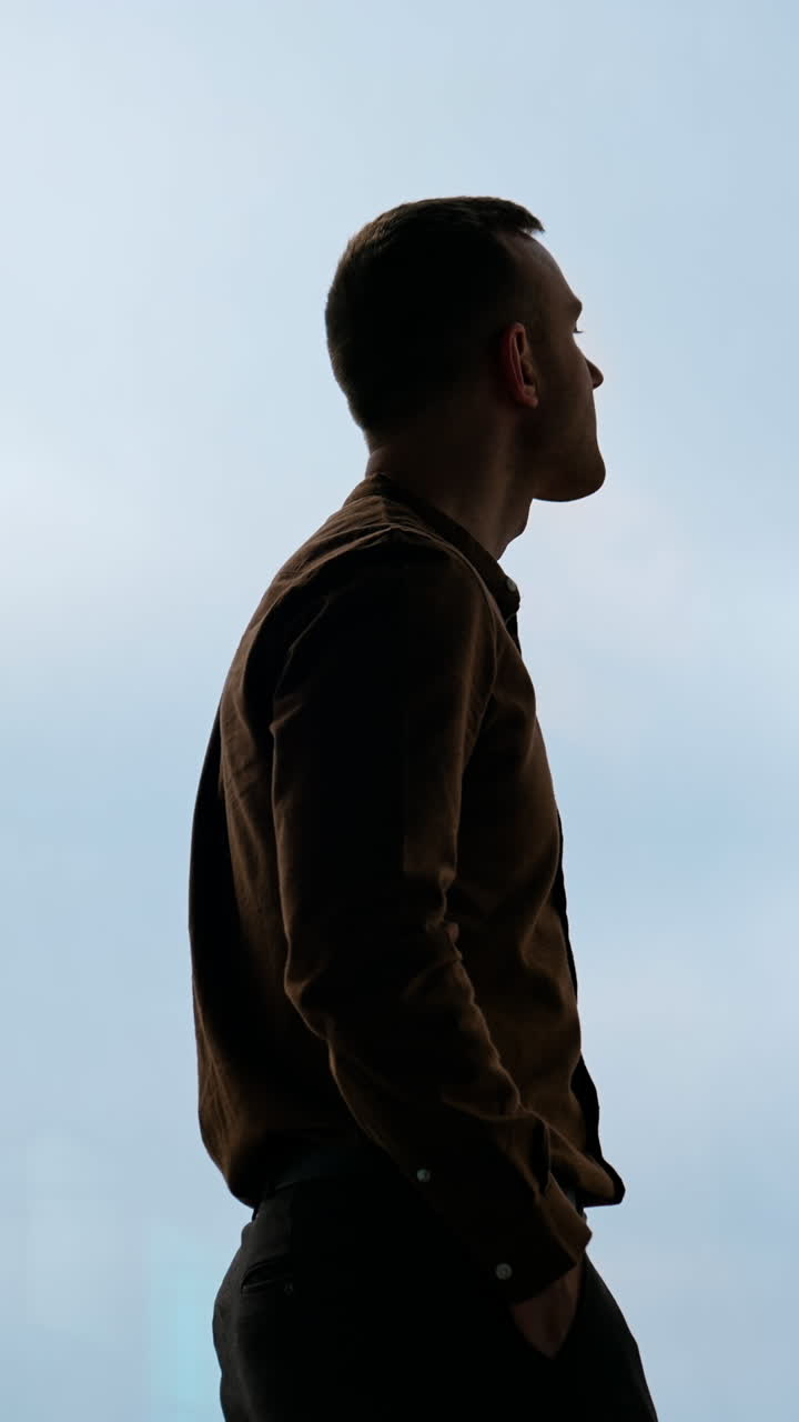A businessman looks out the window in a contemplative way. Vertical video