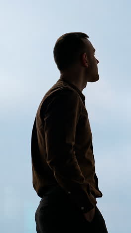 a businessman looks out the window in a contemplative way. vertical video