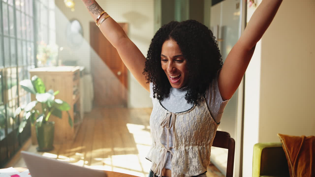 Happy Young Woman Celebrates Success While Working on Laptop at Home