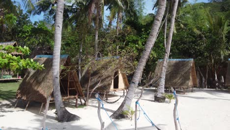 Cabañas-Ecológicas-Sobre-Pilotes-Y-Hamacas-Con-Palmeras-En-La-Playa-Tropical-De-Arena-Blanca