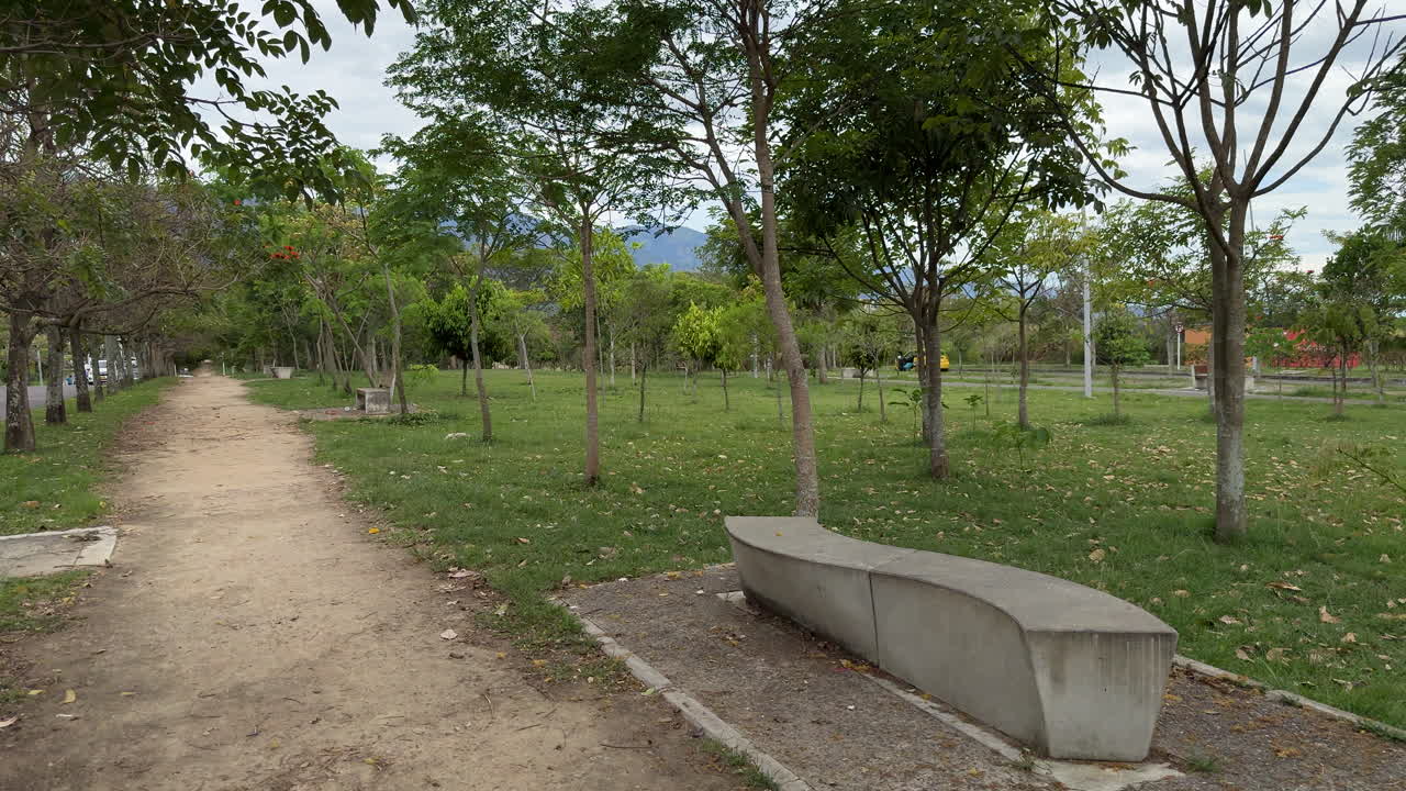 First-person walk through a park with trees and greenery, including a smooth pan to the right. Scenic FPV footage of outdoor leisure, relaxation, and exploration