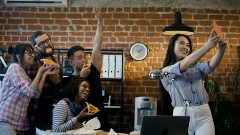 cheerful colleagues taking selfie with pizza