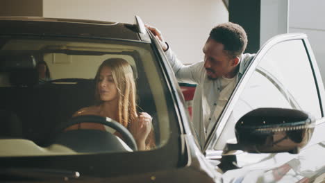 mujer mirando un coche nuevo con un vendedor