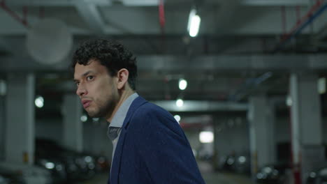 Anxious-and-nervous-man-in-fancy-suit-stares-around-in-underground-parking-lot,-feeling-being-followed