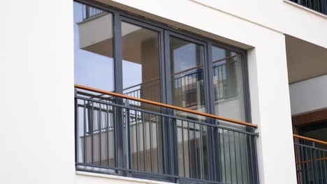 close-up of a modern building's balcony with a glass window and a metal railing