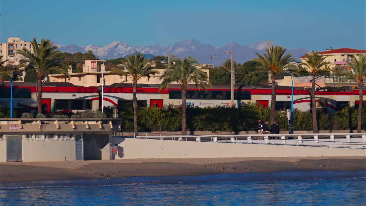 Juan-les-Pins, France - January 25, 2025: Gray train moving on the rails in Antibes, on the coast of the sea