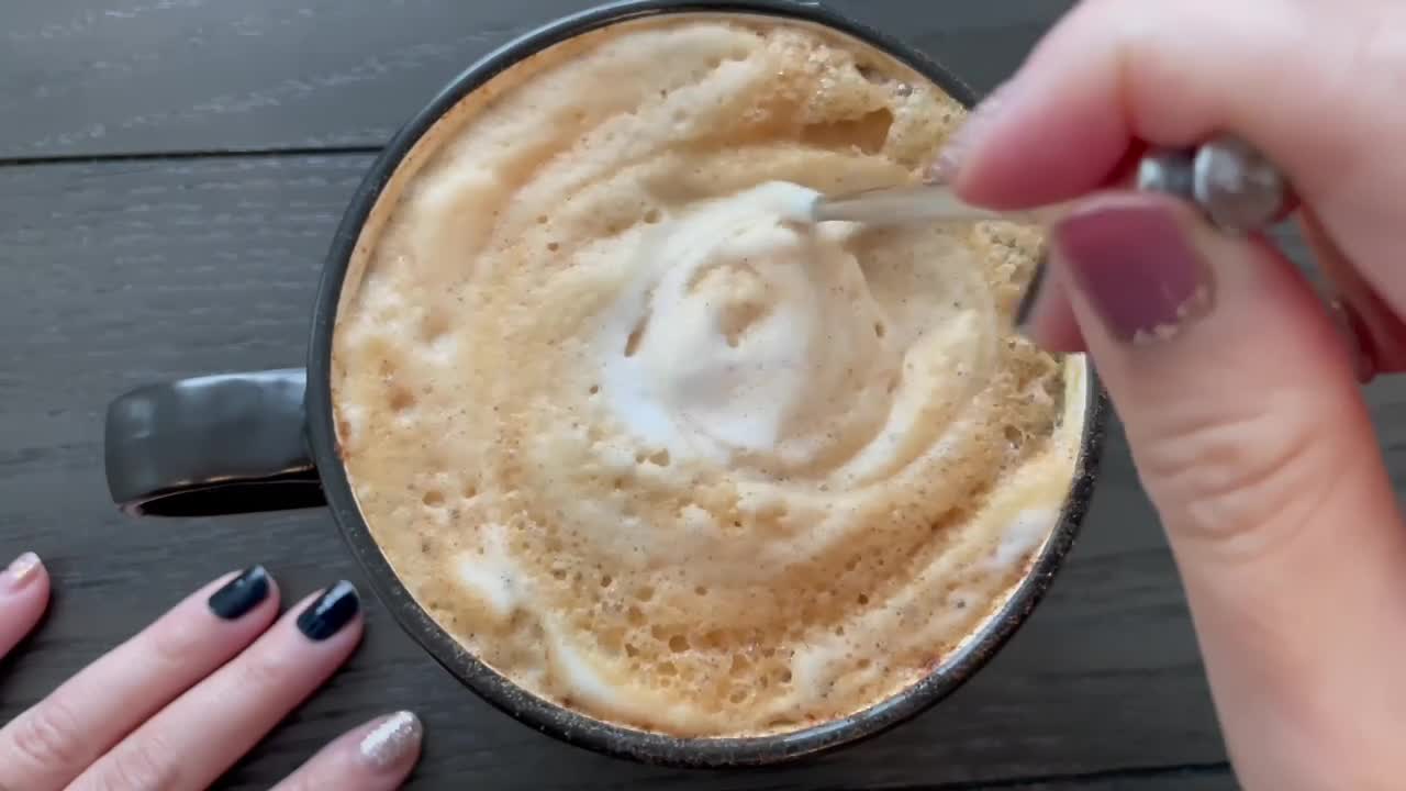 호박 스파이스 라떼의 뜨거운 컵을 휘젓는 여자