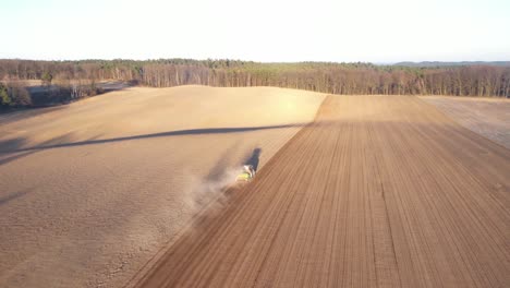 Tractor-working-on-agricultural-plantation-at-sunset