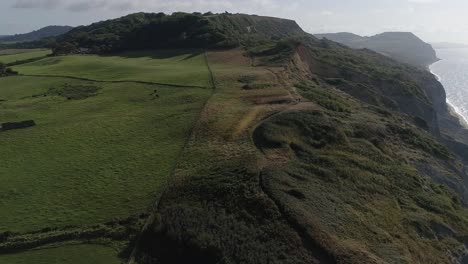 los acantilados de golden cap y charmouth beach se revelan con una trayectoria aérea desde el interior hasta el mar mirando hacia el este.