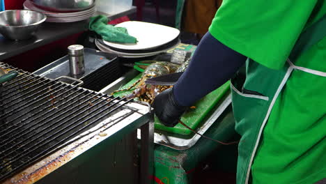 Chef-Asiático-Cortando-Langosta-Arcoíris-Con-Un-Cuchillo-En-Un-Mercado-De-Comida-Callejera