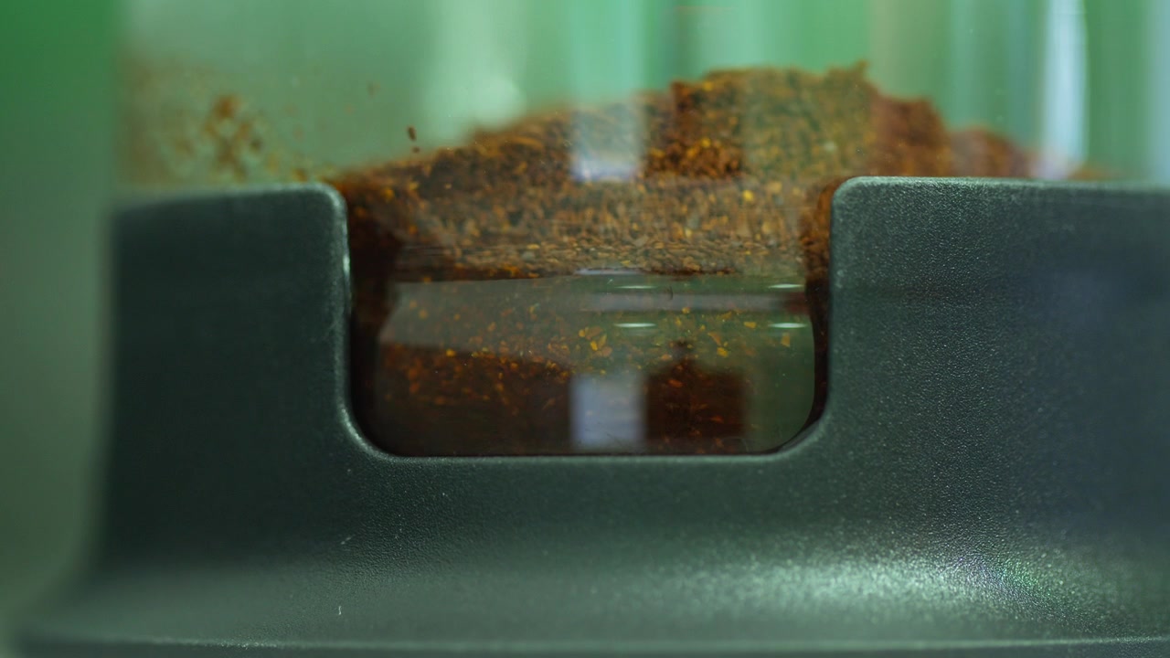 Bidikan makro air yang dituangkan ke dalam French press, bercampur dengan bubuk kopi untuk memulai proses penyeduhan.