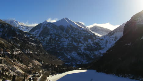 Aerial-Cinematic-Drone-view-of-Telluride-mountain-ski-resort-downtown-Colorado-of-scenic-mountains-landscape,-lake-and-historic-buildings-early-sun-light-mid-winter-to-the-right-movement